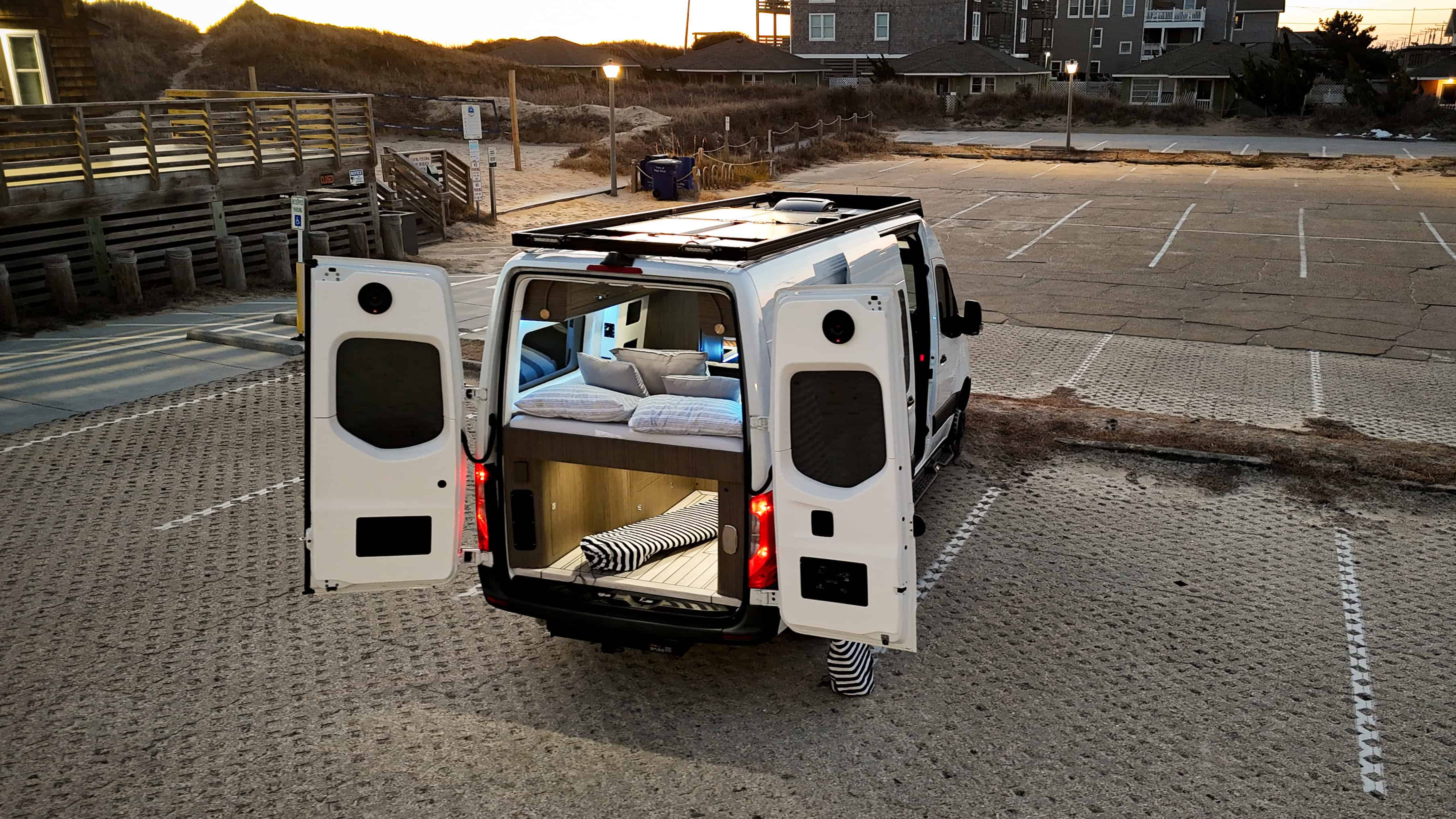 Van van stationné près d’une plage with portes arrière ouvertes montrant bed and storage